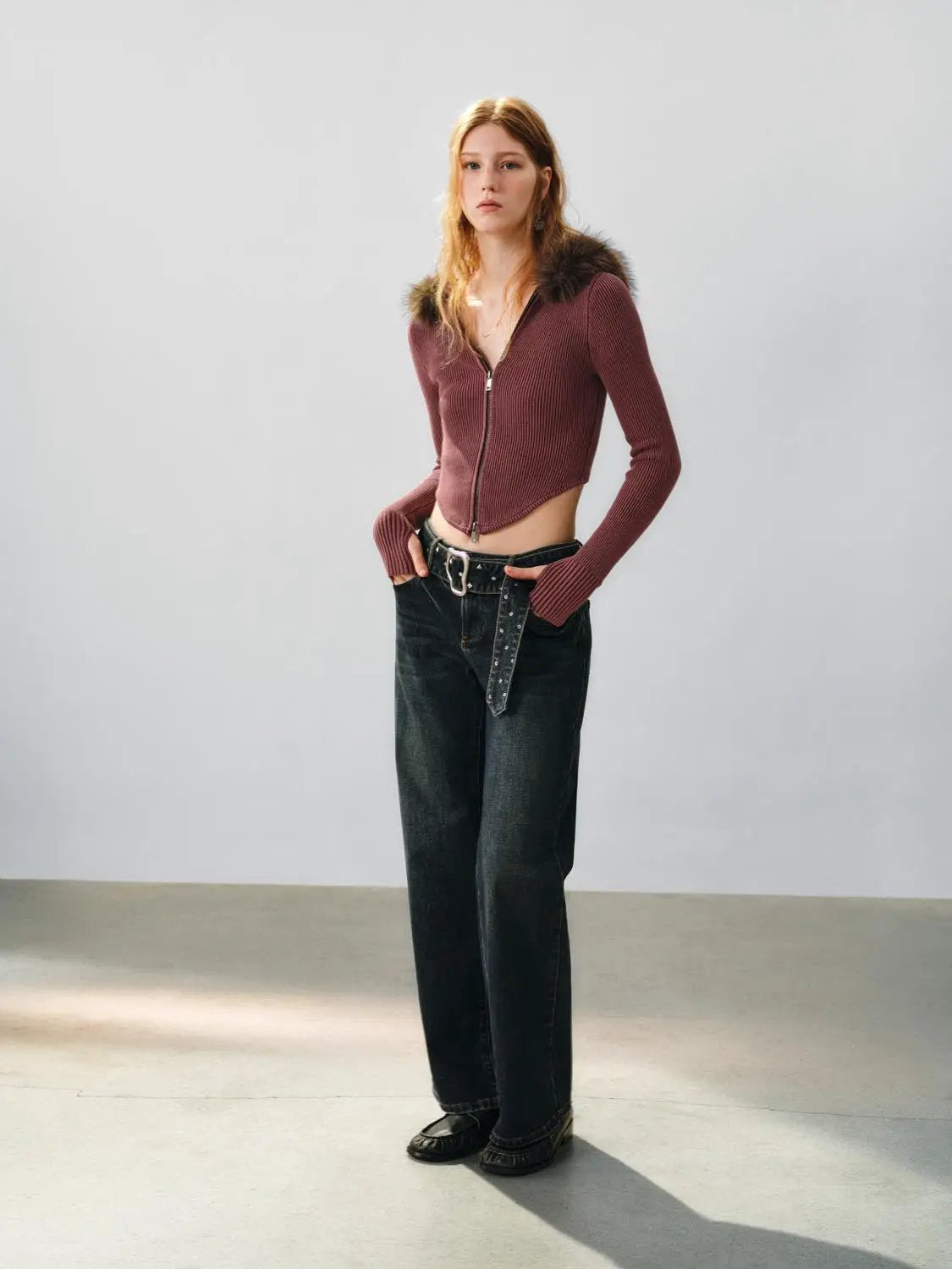 Knit cardigan in maroon ribbed knit, cropped with front zipper; paired with dark jeans.