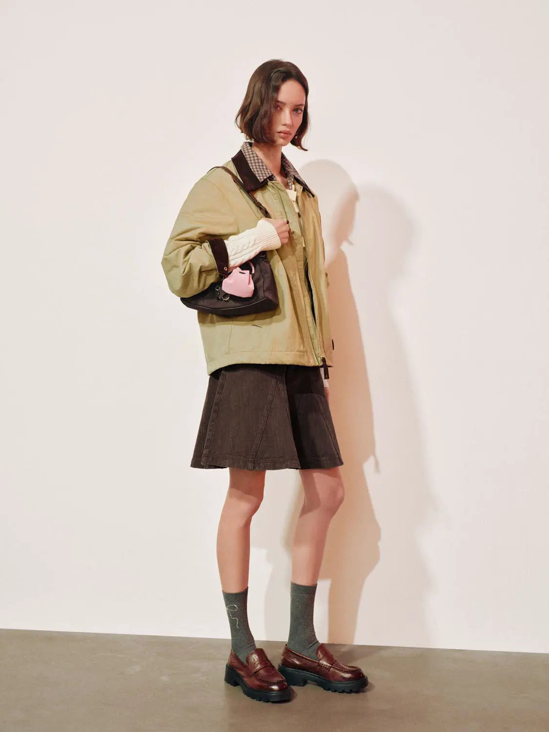 Padded jacket olive-beige with dark brown collar, layered over a checkered shirt.