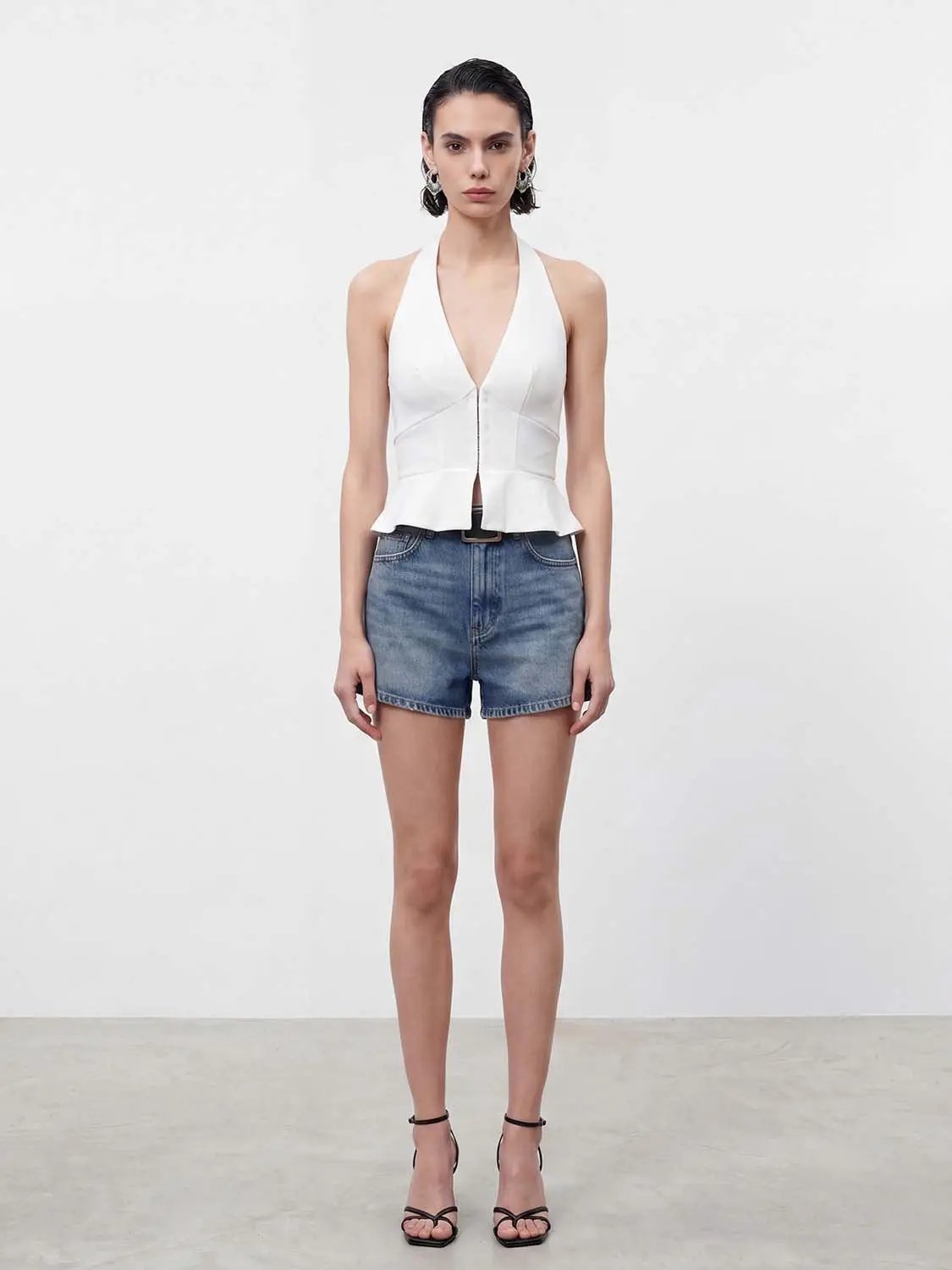Top white halter-neck peplum with front zipper; denim shorts
