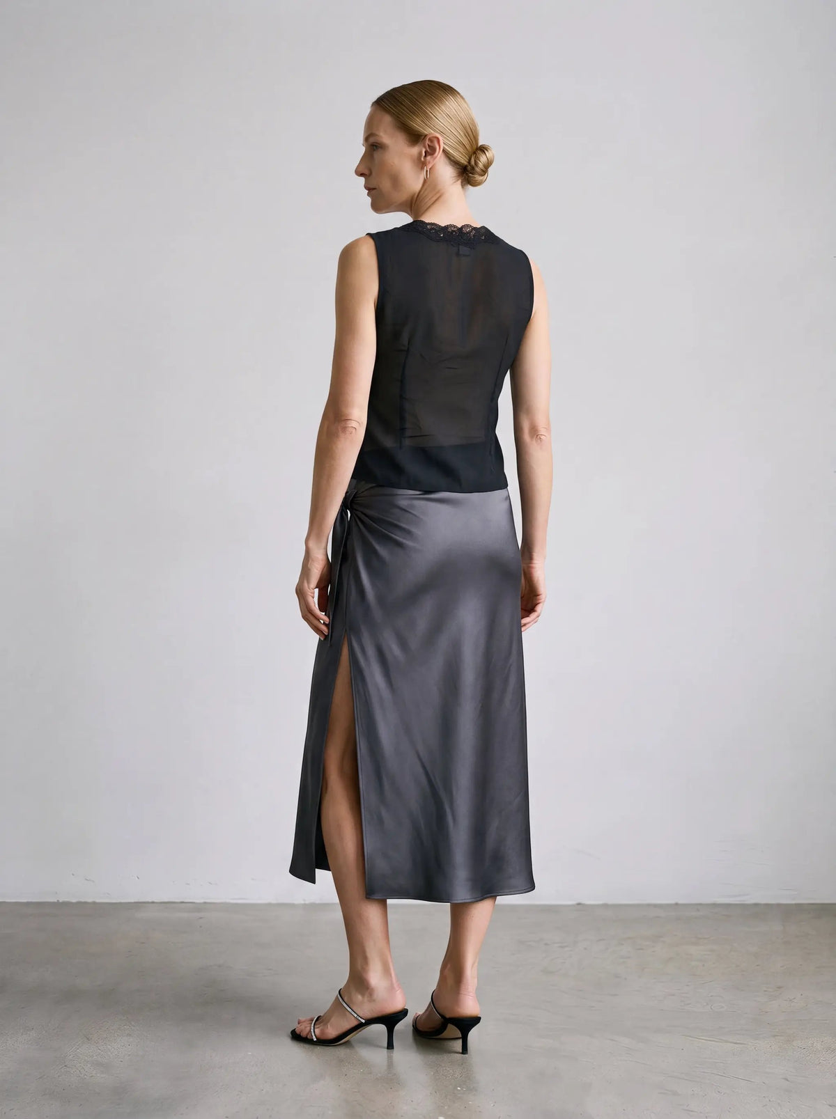 Delicate black lace-trimmed sheer V-neck blouse, sleeveless, back view with lace neckline detail.