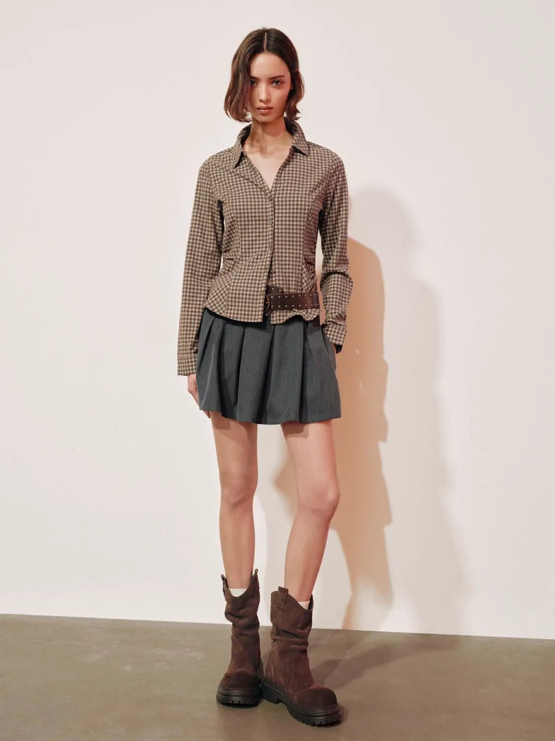 Button-front shirt in brown checkered pattern with gray pleated skirt, brown belt and boots