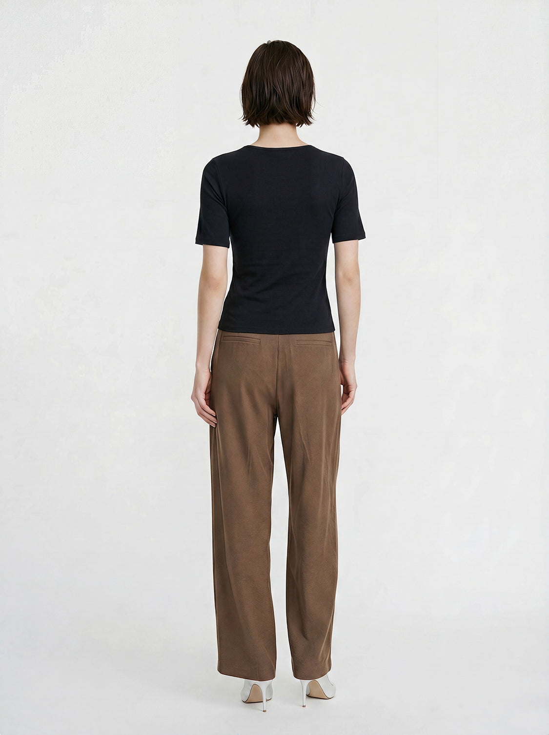 Cotton jersey knit short-sleeve T-shirt in black worn by model, back view with brown trousers