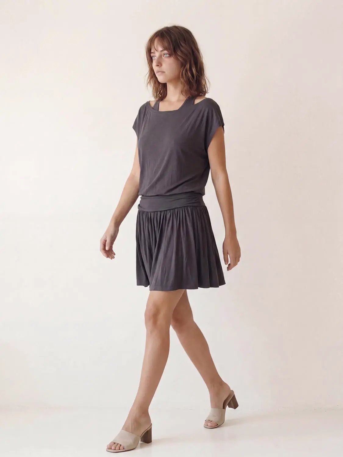 A-Line dress in dark gray with short sleeves, wide waistband, and pleated skirt on model