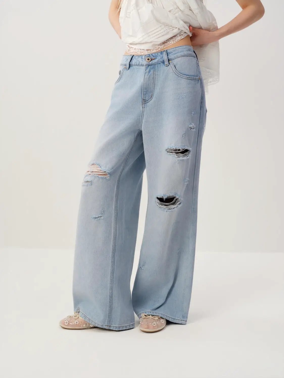 High waisted distressed wide-leg cotton jeans in light blue denim with ripped knees.