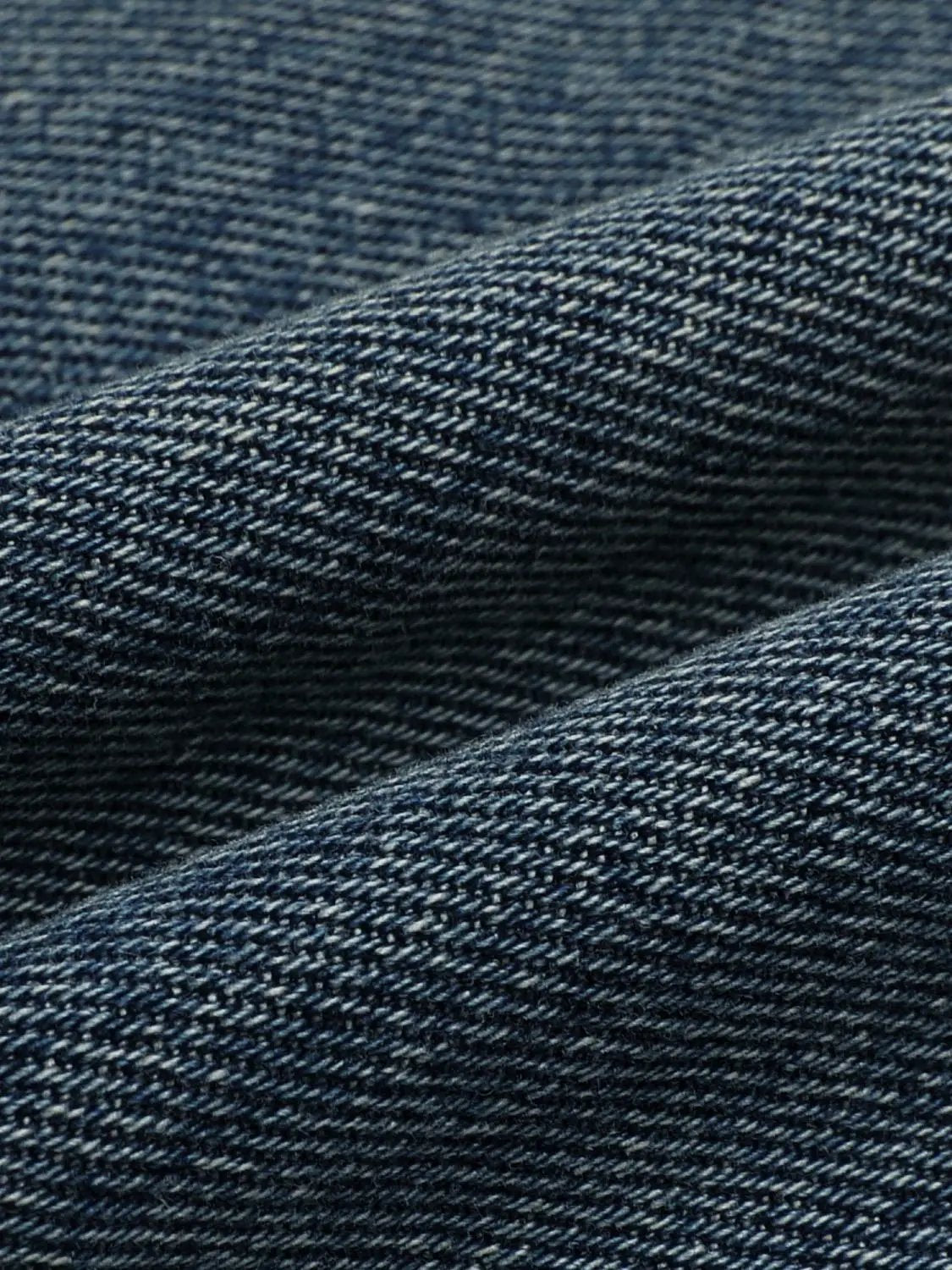 Jeans fabric close-up in dark blue denim with visible weave texture.