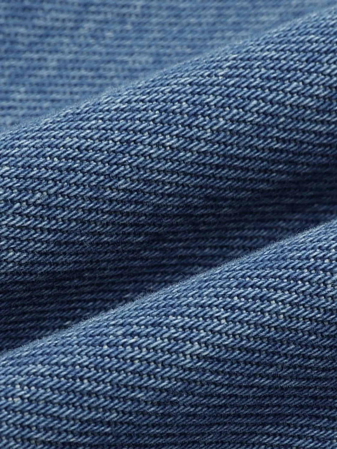 Jeans fabric close-up in blue denim with a textured twill weave.