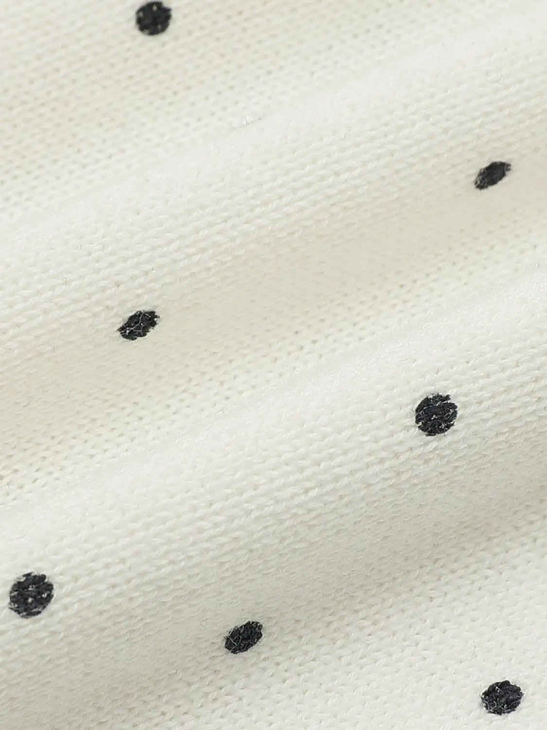 Knitted cardigan fabric in ivory with scattered black polka dots