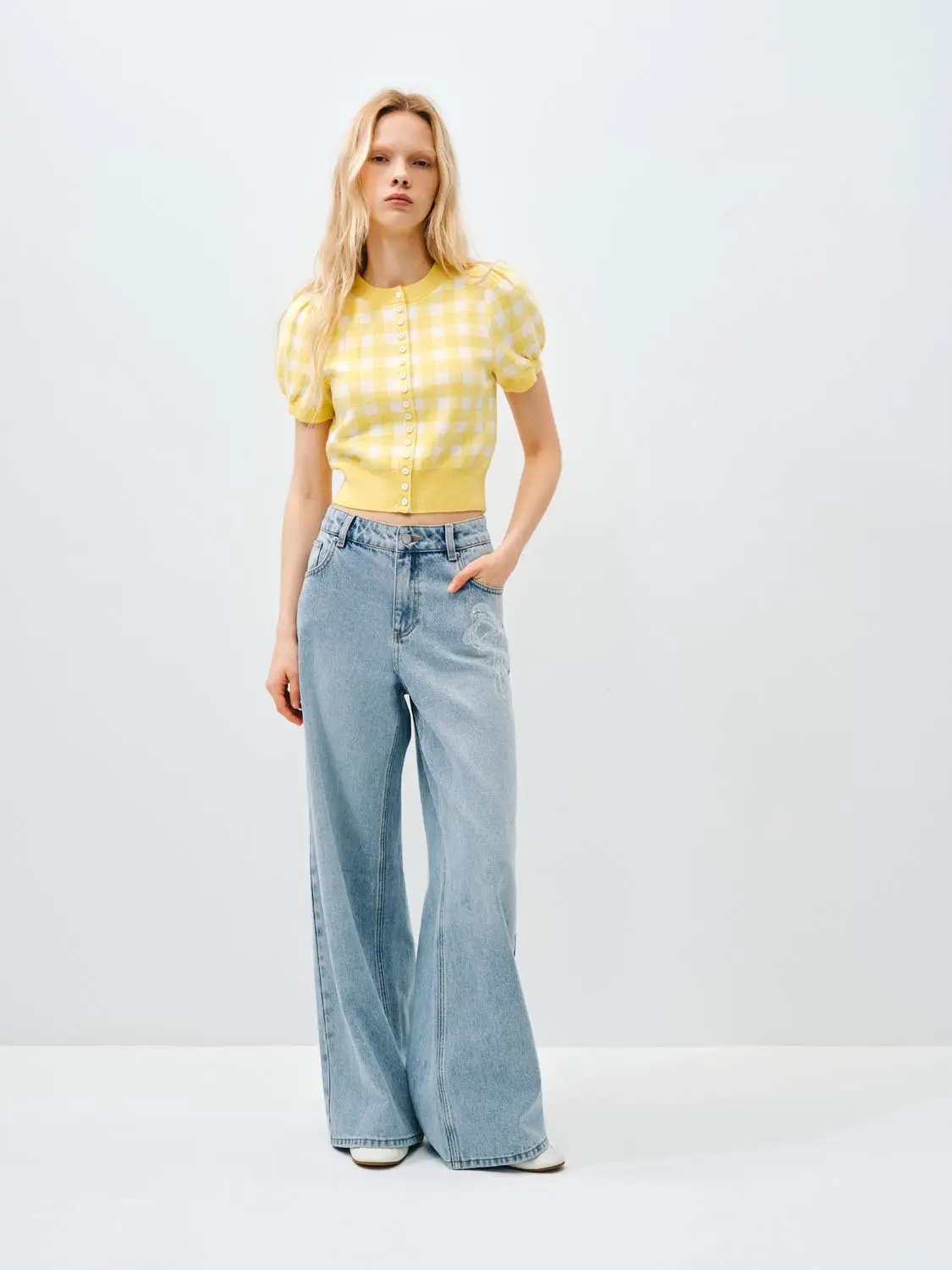 Knitted cardigan in yellow gingham with puff sleeves and button front; paired with light-wash wide-leg jeans.