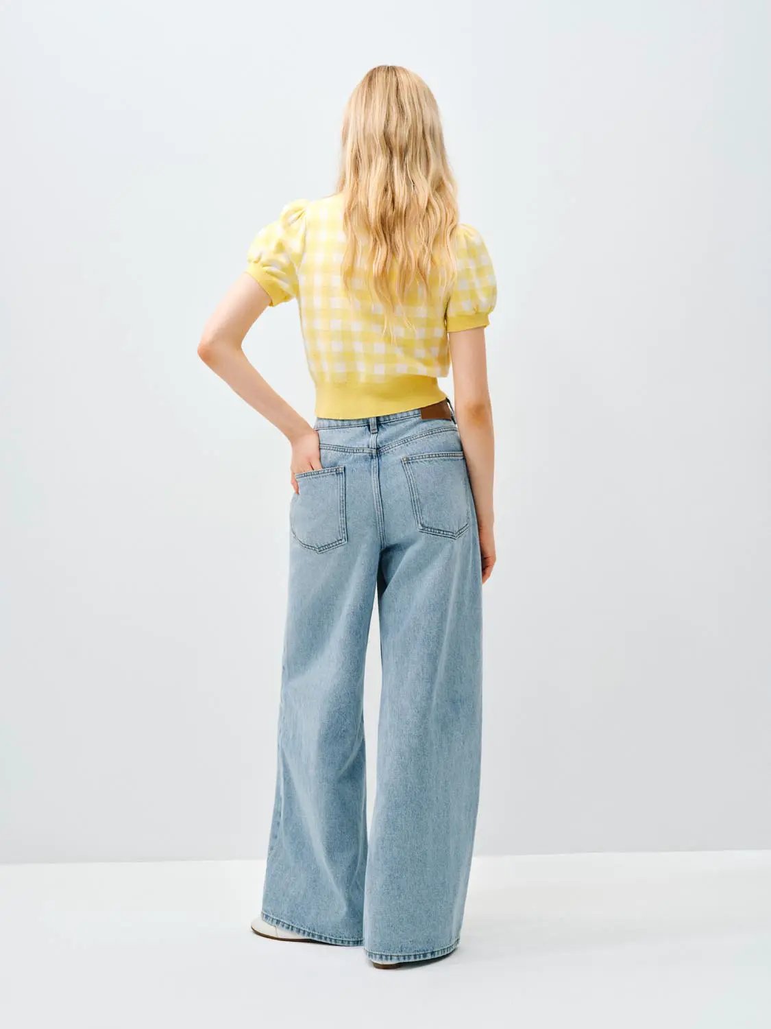 Knitted cardigan in yellow gingham, cropped with short puff sleeves; back view on model showcasing relaxed fit.