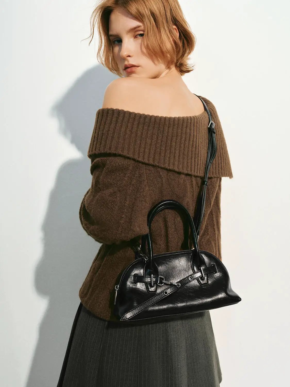 Knitted T-Shirts brown oversized off-shoulder sweater with ribbed collar; model carries black handbag