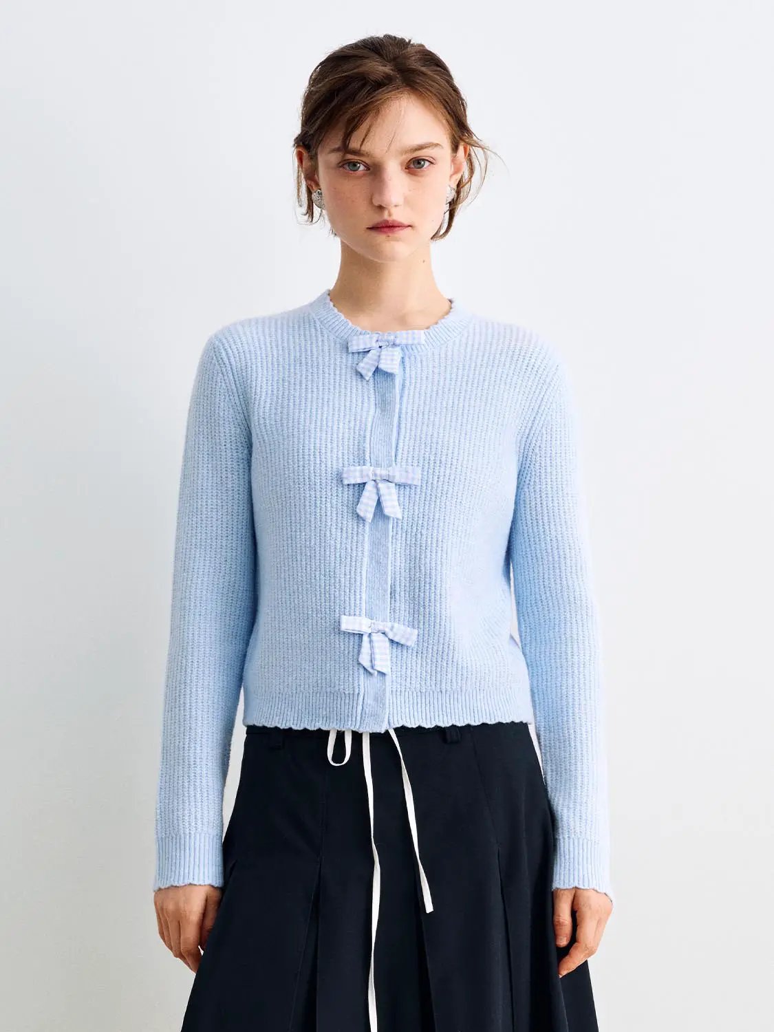Knitted cardigan in light blue with three bow closures along the front