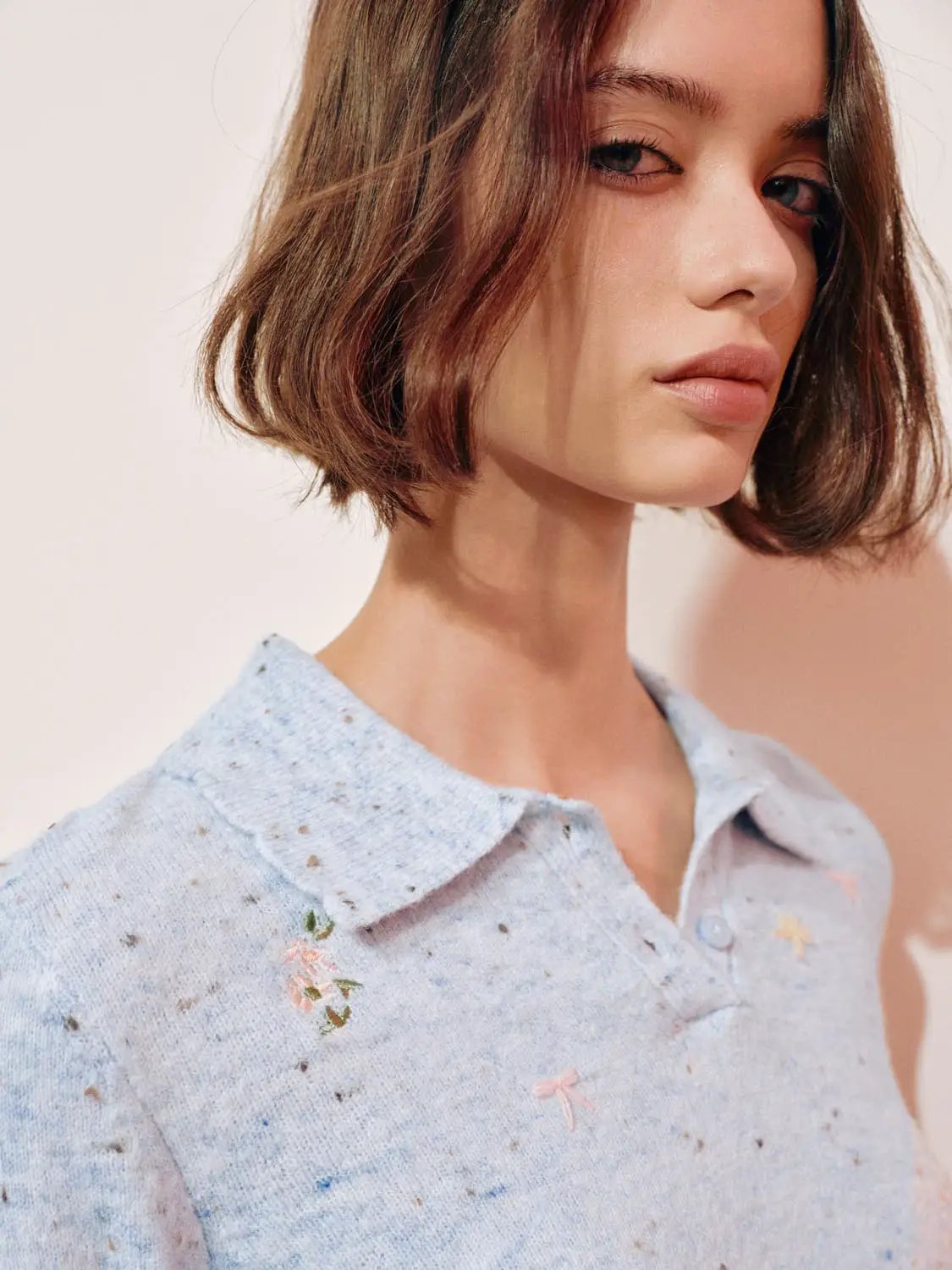 Embroidered floral knit polo collar sweater, light blue speckled knit, long sleeves.