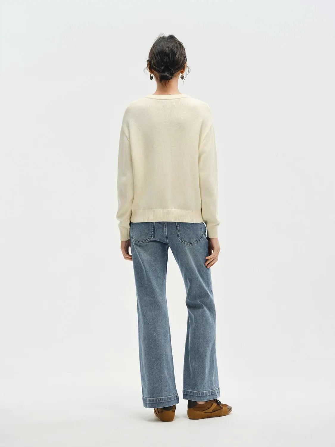 Knit T-Shirts cream knit pullover with long sleeves, paired with blue denim jeans.