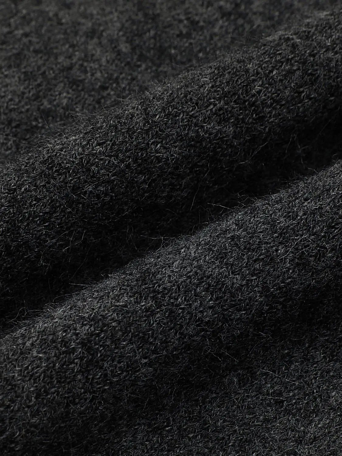 Knitted cardigan fabric in black, close-up of fuzzy textured fibers